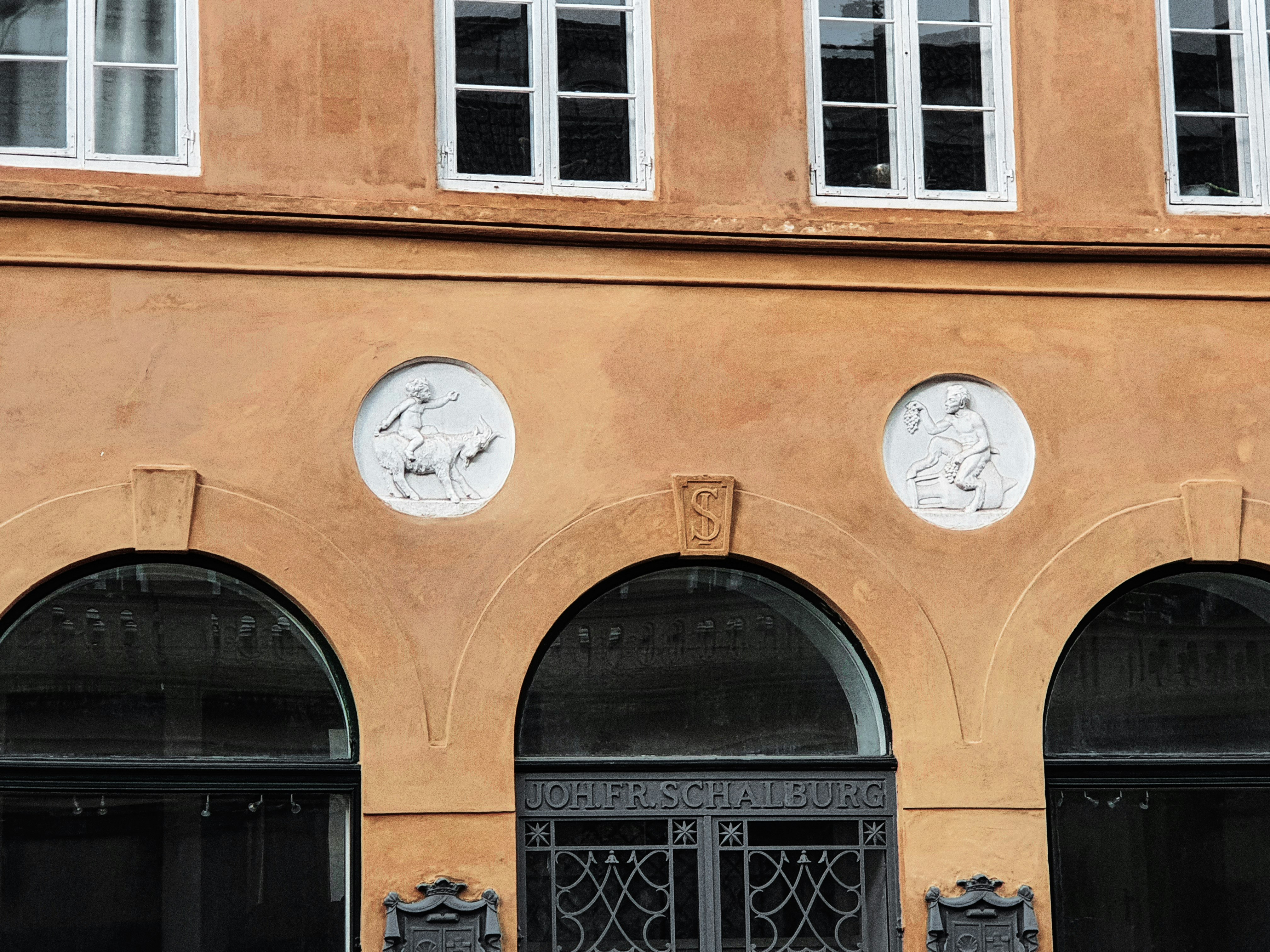 Orange building facade with arched windows and circular reliefs.